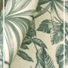 Green tropical leaf print curtain fabric on neutral base with pearl tieback, botanical palm pattern drapes for modern interiors.