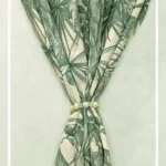 Green tropical leaf print curtain fabric on neutral base with pearl tieback, botanical palm pattern drapes for modern interiors.