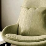 Soft olive green sofa upholstery fabric on cushioned lounge chair with smooth textured finish for modern living room seating