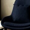 Dark navy blue upholstered lounge chair with cushioned seat and curved backrest on metal legs in a modern interior setting