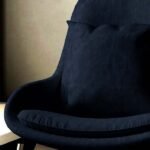 Dark navy blue upholstered lounge chair with cushioned seat and curved backrest on metal legs in a modern interior setting