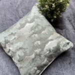 Luxury abstract textured cushion cover fabric in soft sage green with subtle metallic sheen, styled for elegant modern interiors.