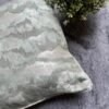 Luxury abstract textured cushion cover fabric in soft sage green with subtle metallic sheen, styled for elegant modern interiors.