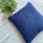 Luxury navy blue textured cushion upholstery fabric with plush boucle finish, styled on a neutral base with greenery for premium interiors