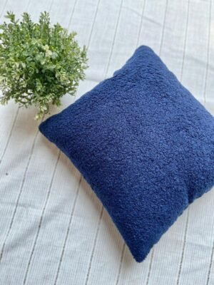Luxury navy blue textured cushion upholstery fabric with plush boucle finish, styled on a neutral base with greenery for premium interiors
