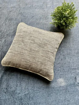 Luxury beige textured cushion upholstery fabric with subtle linear weave, styled on a grey surface with greenery for premium modern interiors