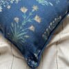 Luxury blue floral cushion cover fabric with delicate botanical motifs in soft green and beige, styled on neutral bedding for premium interior décor.