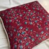 Luxury maroon floral cushion cover fabric with intricate teal and ivory botanical motifs, styled for elegant premium interiors.