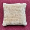 Luxury neutral beige velvet cushion cover with soft textured upholstery fabric, styled on a rich burgundy carpet for premium interior décor.