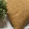Luxury caramel bouclé cushion cover fabric with rich textured upholstery, styled on neutral bedding for premium interior décor.