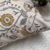 Luxury floral designer fabric in beige with mustard and grey botanical motifs, used for bespoke cushion covers styled on a modern premium bedroom setting.