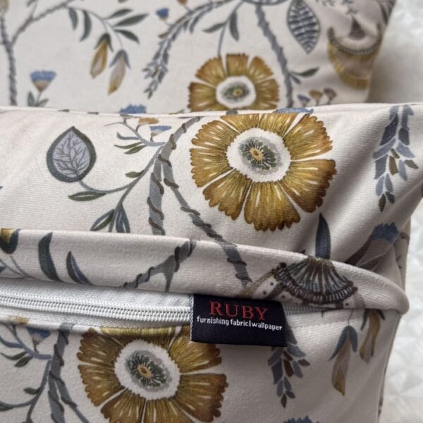 Luxury floral designer fabric in beige with mustard and grey botanical motifs, used for bespoke cushion covers styled on a modern premium bedroom setting.