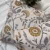 Luxury floral designer fabric in beige with mustard and grey botanical motifs, used for bespoke cushion covers styled on a modern premium bedroom setting.
