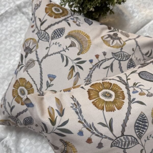 Luxury floral designer fabric in beige with mustard and grey botanical motifs, used for bespoke cushion covers styled on a modern premium bedroom setting.