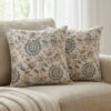 Luxury cream cushion covers with elegant blue floral and vine pattern in premium woven fabric, styled for sophisticated living room and bedroom interiors.