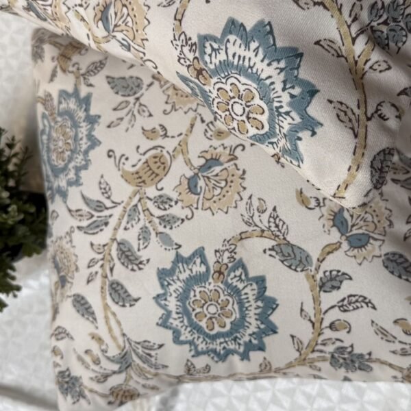 Luxury cream cushion covers with elegant blue floral and vine pattern in premium woven fabric, styled for sophisticated living room and bedroom interiors.