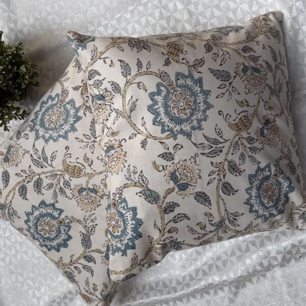 Luxury cream cushion covers with elegant blue floral and vine pattern in premium woven fabric, styled for sophisticated living room and bedroom interiors.