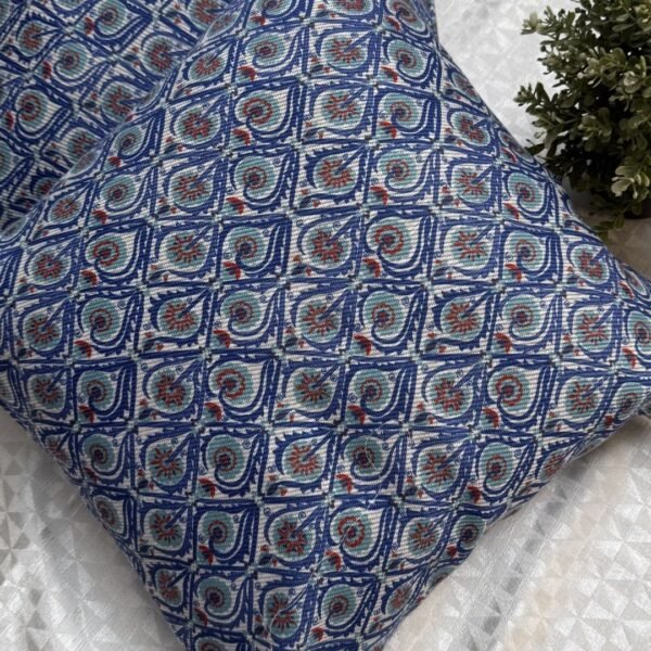 Luxury blue geometric patterned designer cushion with intricate swirl motifs styled on textured wallpaper background, premium interior decor inspiration.