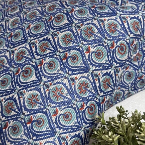 Luxury blue geometric patterned designer cushion with intricate swirl motifs styled on textured wallpaper background, premium interior decor inspiration.