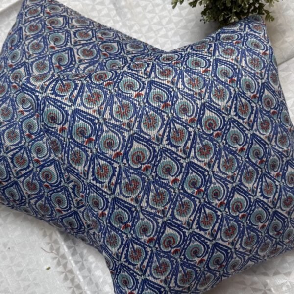 Luxury blue geometric patterned designer cushion with intricate swirl motifs styled on textured wallpaper background, premium interior decor inspiration.