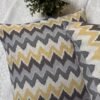 Luxury mustard and grey chevron designer cushion covers in premium fabric placed on white textured bedding, modern bespoke home decor accent pillows