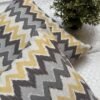 Luxury mustard and grey chevron designer cushion covers in premium fabric placed on white textured bedding, modern bespoke home decor accent pillows