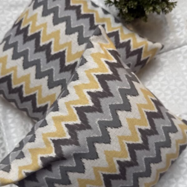 Luxury mustard and grey chevron designer cushion covers in premium fabric placed on white textured bedding, modern bespoke home decor accent pillows