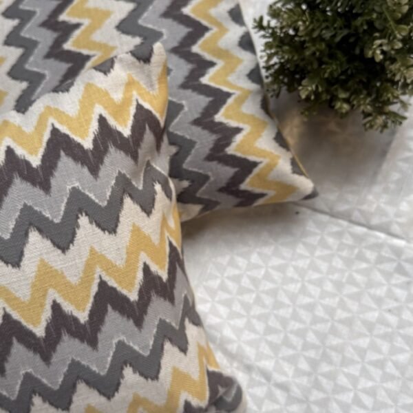 Luxury mustard and grey chevron designer cushion covers in premium fabric placed on white textured bedding, modern bespoke home decor accent pillows