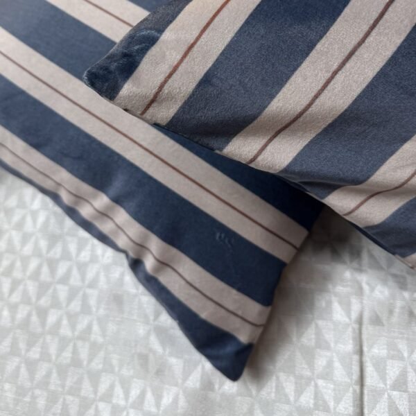 Luxury navy and ivory striped designer cushion covers styled against textured geometric wallpaper with decorative greenery, premium modern interior styling inspiration.
