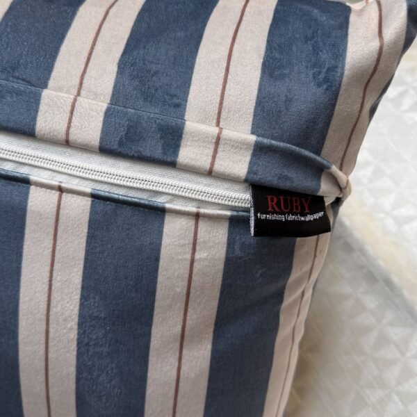 Luxury navy and ivory striped designer cushion covers styled against textured geometric wallpaper with decorative greenery, premium modern interior styling inspiration.