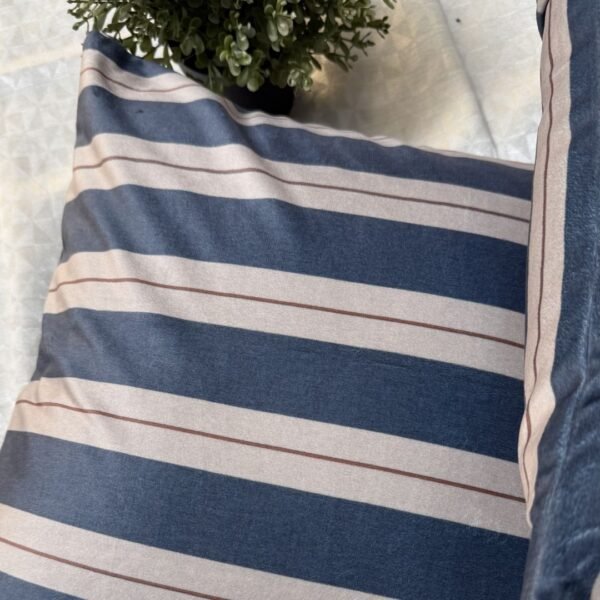 Luxury navy and ivory striped designer cushion covers styled against textured geometric wallpaper with decorative greenery, premium modern interior styling inspiration.