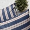 Luxury navy and ivory striped designer cushion covers styled against textured geometric wallpaper with decorative greenery, premium modern interior styling inspiration.