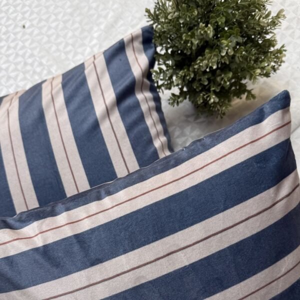 Luxury navy and ivory striped designer cushion covers styled against textured geometric wallpaper with decorative greenery, premium modern interior styling inspiration.