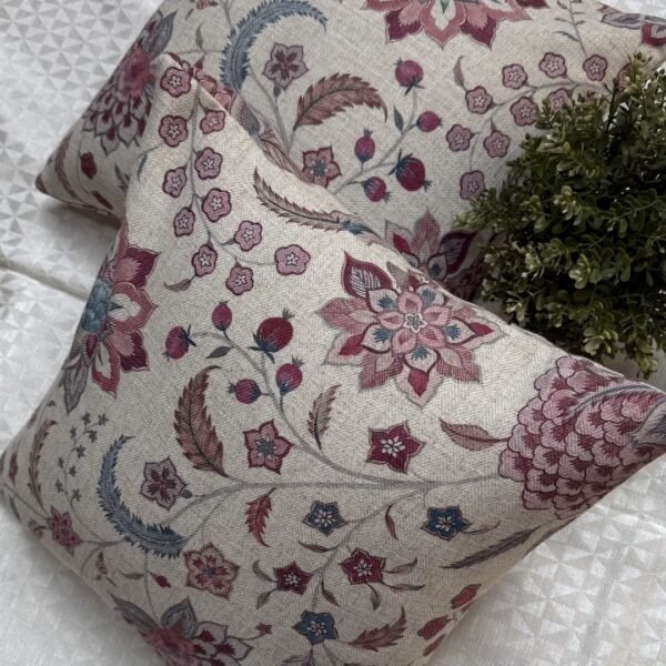 Luxury floral cushion cover in beige woven fabric with pink, burgundy and blue botanical pattern, premium soft furnishing accent for elegant living room and bedroom interiors.