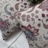 Luxury floral cushion cover in beige woven fabric with pink, burgundy and blue botanical pattern, premium soft furnishing accent for elegant living room and bedroom interiors.