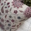 Luxury floral cushion cover in beige woven fabric with pink, burgundy and blue botanical pattern, premium soft furnishing accent for elegant living room and bedroom interiors.