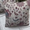 Luxury floral cushion cover in beige woven fabric with pink, burgundy and blue botanical pattern, premium soft furnishing accent for elegant living room and bedroom interiors.