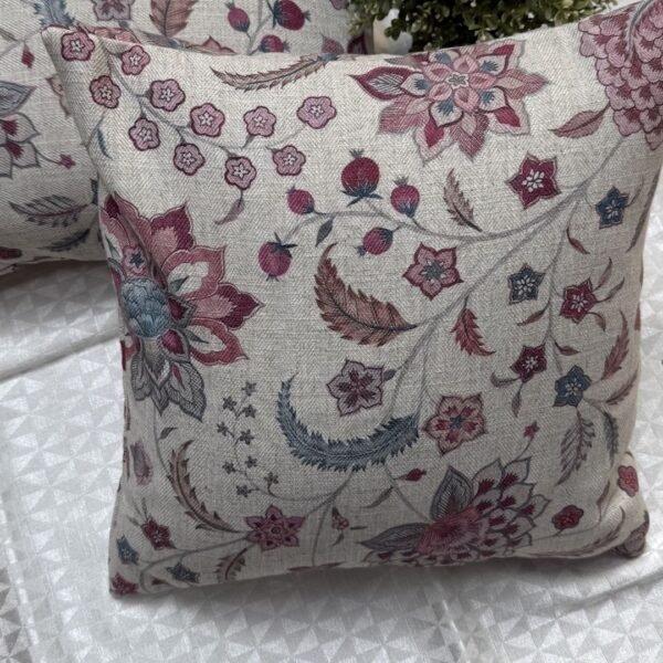 Luxury floral cushion cover in beige woven fabric with pink, burgundy and blue botanical pattern, premium soft furnishing accent for elegant living room and bedroom interiors.