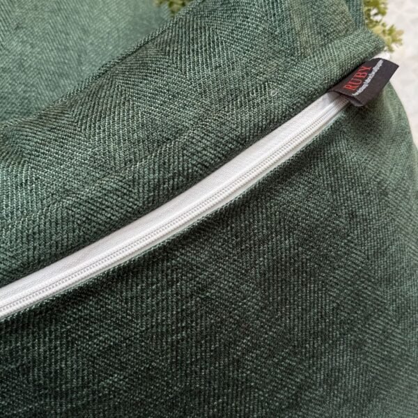 Luxury sage green textured cushion cover in premium woven fabric with subtle chevron pattern, elegant soft furnishing for modern living room and upscale interiors.