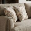 Premium designer cushion covers in beige cotton fabric featuring hand-block style rust floral motifs with sage green leaves, styled for luxury living room and bedroom interiors.