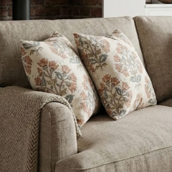 Premium designer cushion covers in beige cotton fabric featuring hand-block style rust floral motifs with sage green leaves, styled for luxury living room and bedroom interiors.