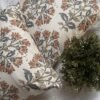 Premium designer cushion covers in beige cotton fabric featuring hand-block style rust floral motifs with sage green leaves, styled for luxury living room and bedroom interiors.