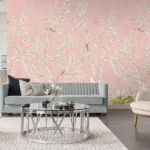 Soft blush pink floral mural wallpaper with delicate white botanical branches and birds, styled in a modern luxury living room with a grey sofa and glass coffee table