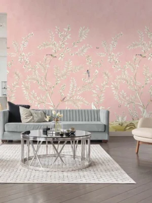 Soft blush pink floral mural wallpaper with delicate white botanical branches and birds, styled in a modern luxury living room with a grey sofa and glass coffee table