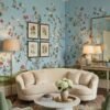 Daisy Bennett floral bird mural wallpaper on soft blue background in elegant bedroom with upholstered bed, pastel cushions and classic wooden side tables