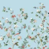 Daisy Bennett floral bird mural wallpaper on soft blue background in elegant bedroom with upholstered bed, pastel cushions and classic wooden side tables
