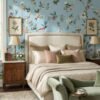 Daisy Bennett floral bird mural wallpaper on soft blue background in elegant bedroom with upholstered bed, pastel cushions and classic wooden side tables