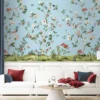 Daisy Bennett floral bird mural wallpaper on soft blue background in elegant bedroom with upholstered bed, pastel cushions and classic wooden side tables