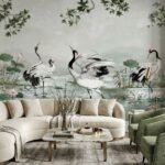 Luxury neutral grey mural wallpaper featuring elegant cranes, lotus flowers, and botanical branches in a serene landscape design, styled in a modern living room with beige sofa and green armchairs by RUBY Furnishing Studio Ghatkopar East Mumbai.