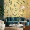 Floral bird wallpaper design with yellow background in modern living room featuring teal velvet sofa, decorative cushions and elegant home décor